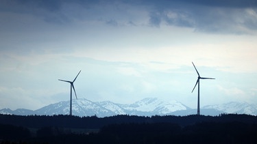 Zwei Windräder stehen vor schneebedeckten Alpen. | Bild: picture alliance/dpa | Karl-Josef Hildenbrand