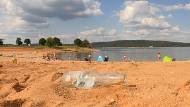 Eine leere Bierflasche liegt am Strand des Brombachsees | Bild: BR