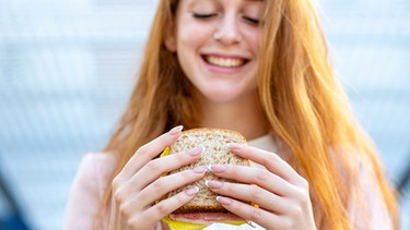 Frau hält Sandwich mit veganer Wurst in den Händen | Bild: mauritius images / Westend61 / Emma Innocenti